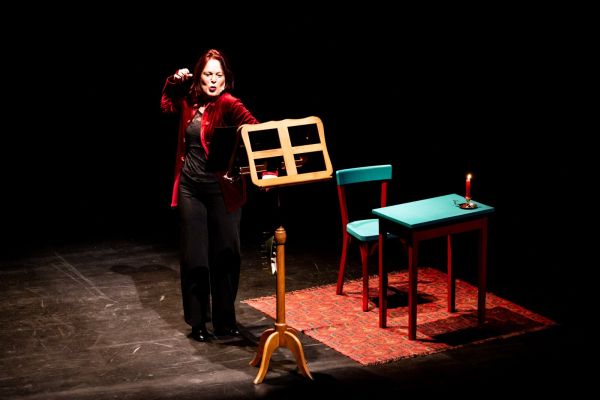 Scène de théâtre : le piano à gauche, la récitante à droite, une illustration projetée au fond